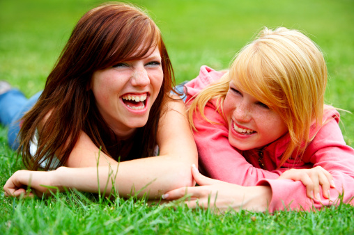 Two young teens relaxing in a park.