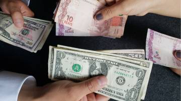 Notas de real e dólar sendo trocadas