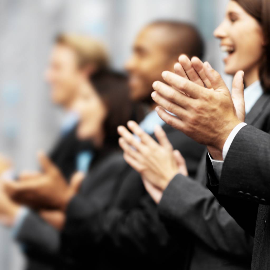 Side profile of a group of young executives clapping (blurred)