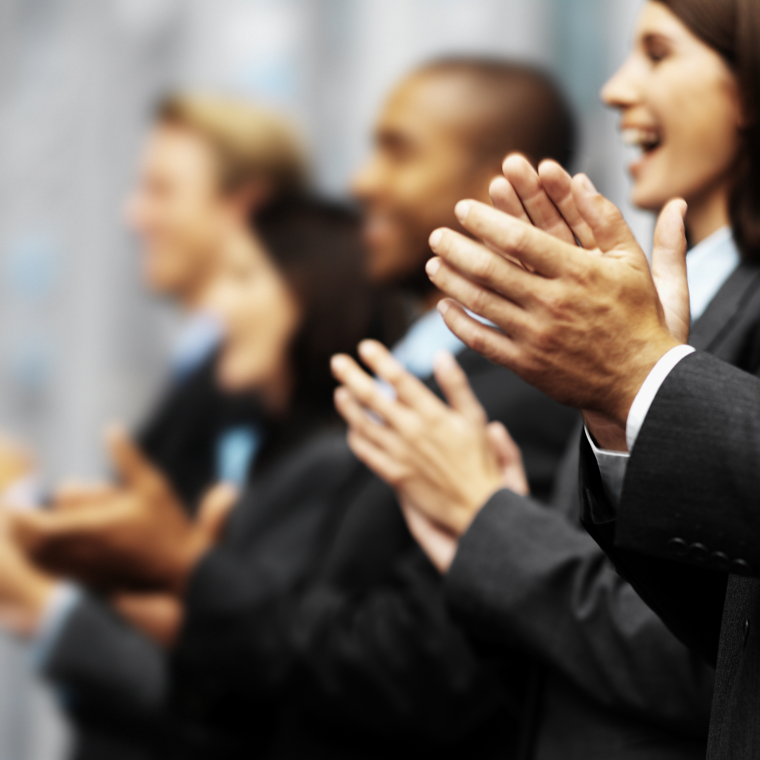 Side profile of a group of young executives clapping (blurred)