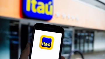 Aplicativo do Itaú em primeiro plano; no segundo plano uma agência do banco