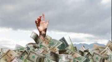 Uma pessoa se afogando em dólares
