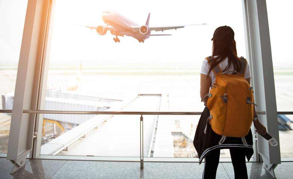 Passageira observa avião em aeroporto (Foto: Shutterstock)