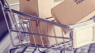 Carrinho de compras em cima de um teclado de notebook com caixas de papelão dentro dele