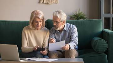 Serious mature couple calculating bills, checking domestic finances