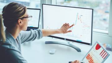 Business woman study financial market to calculate possible risks and profits.Female economist accounting money with statistics graphs pointing on screen of computer at desktop. Quotations on exchange