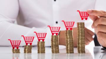 Businessperson placing shopping cart over stacked coins