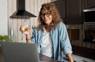 Mulher bebendo vinho e usando o computador (Matilda Wormwood/Pexels)