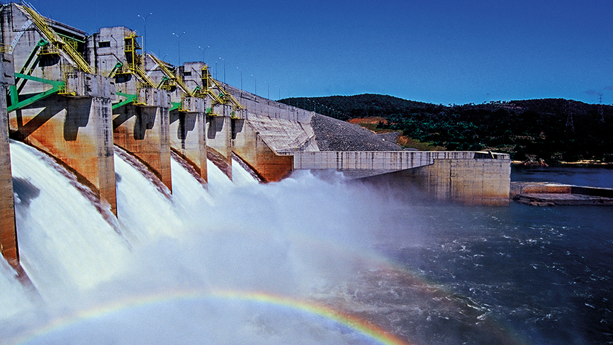 A rainbow forms in the spillway of a dam