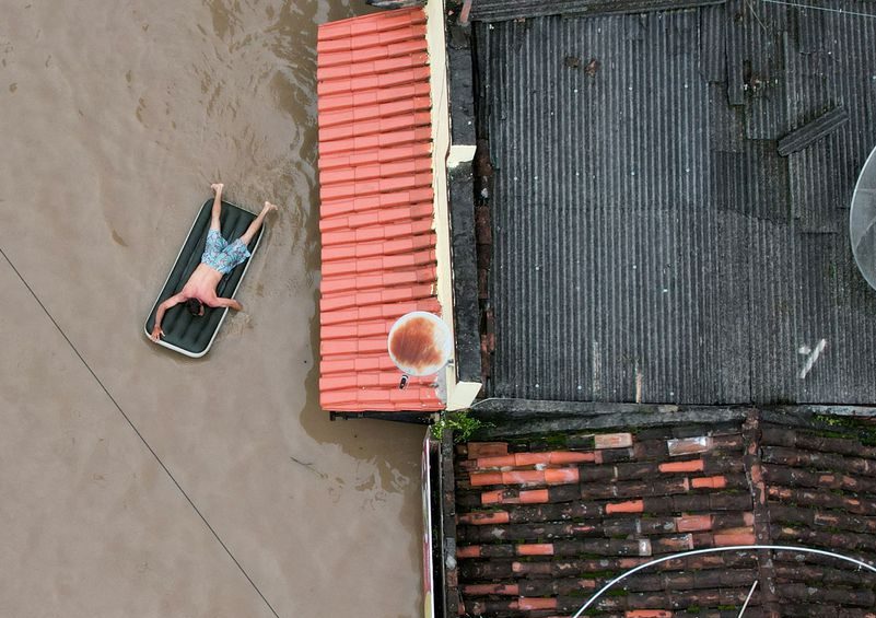 Homem é visto sobre colchão inflável em área alagada de Itabuna, no sul da Bahia (Crédito: Leonardo Benassatto/Reuters) 