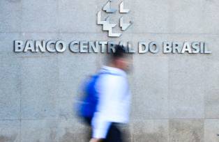Foto em que um homem passa na frente do prédio do Banco Central do Brasil