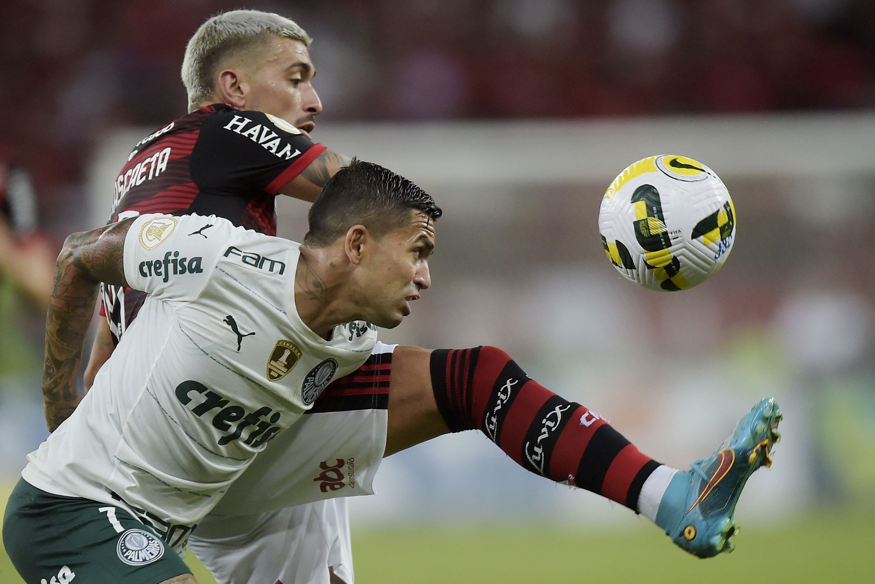 Dudu e de Arrascaeta disputam bola em jogo entre Flamengo e Palmeiras no Brasileiro de 2022; clubes foram campeões em arrecadação no futebol brasileiro em 2021 (Alexandre Loureiro/Getty Images)