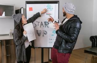 Dois empreendedores, um homem e uma mulher, apresentam um negócio para investidores de startup
