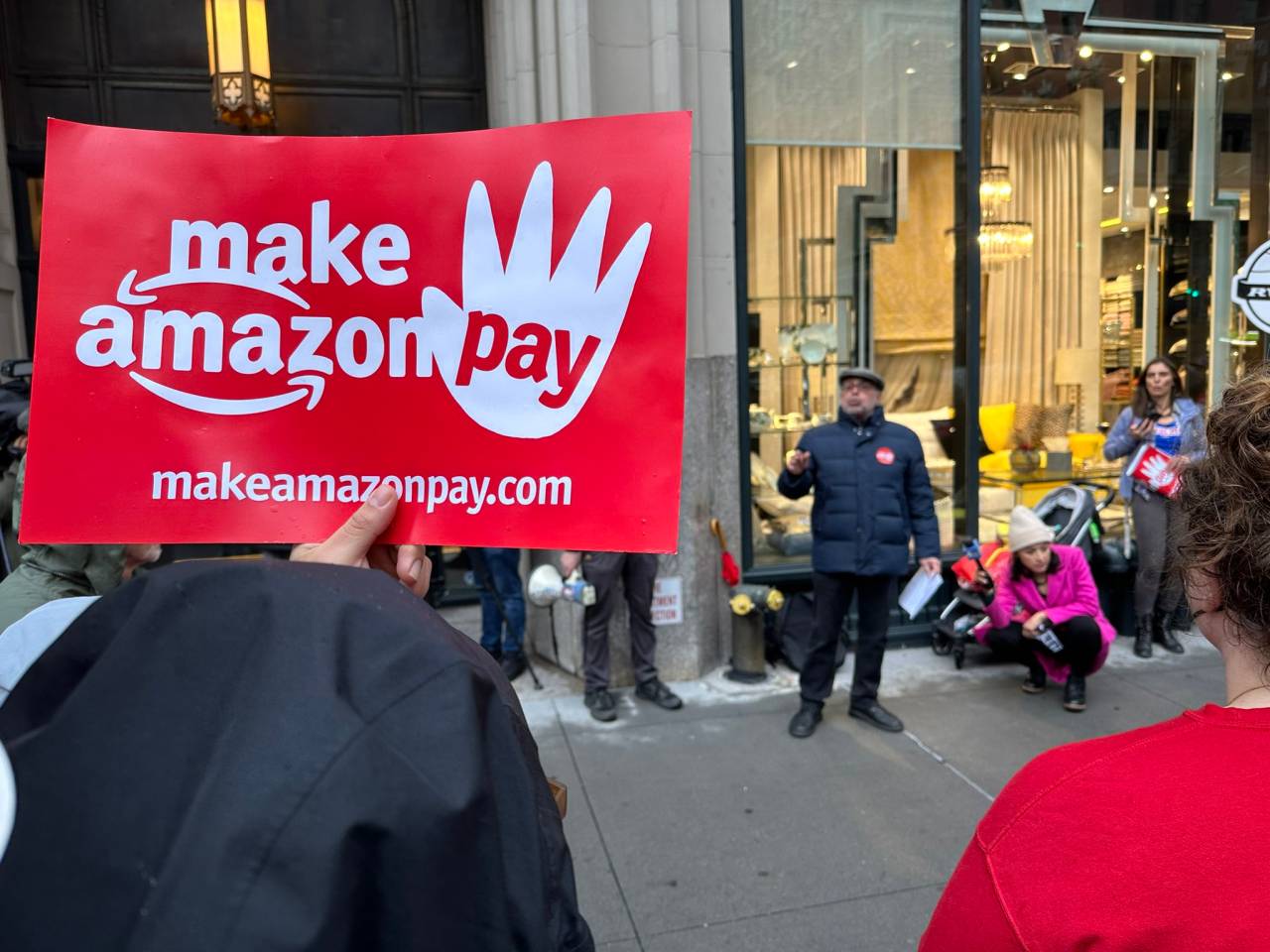 Manifestantes levantam cartazes com a frase "Faça a Amazon Pagar", na tradução para português. Foto: Redes sociais