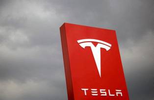 Fachada com logotipo da Tesla com céu nublado ao fundo
