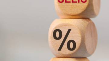 The SELIC acronym and the percentage symbol on wooden dice lying on top of a calculator.