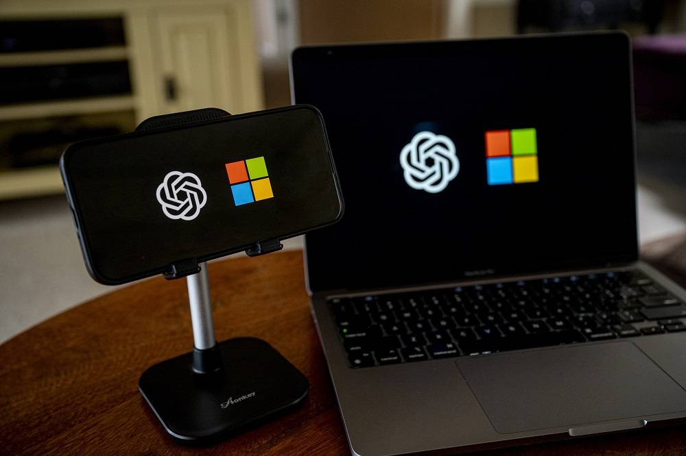 Os logotipos da OpenAI e da Microsoft em um smartphone e laptop (David Paul Morris/Bloomberg)