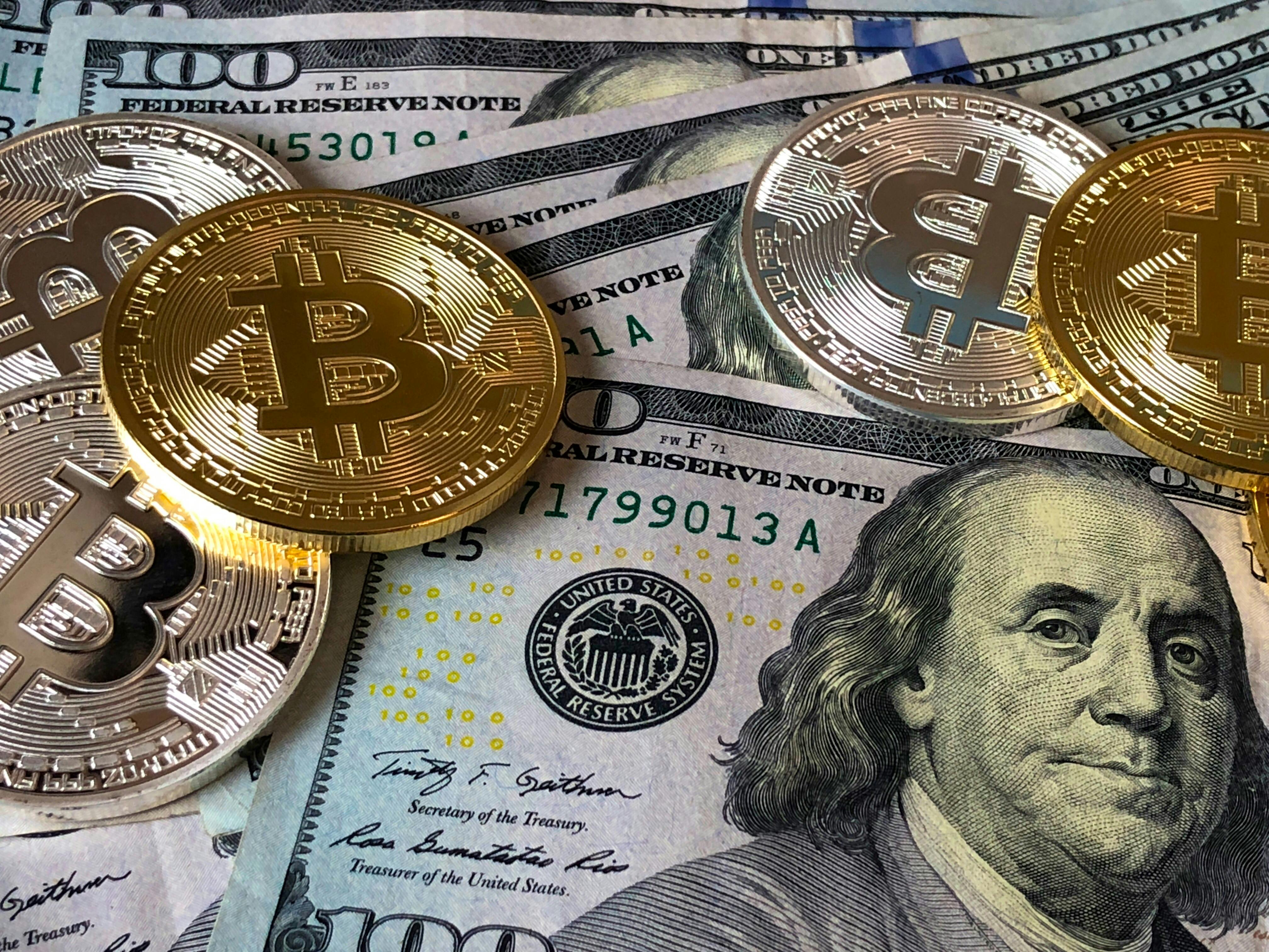 Representação de diversificação de ativos com dólares e representações físicas de Bitcoin e criptoativos (Foto: Pexels)