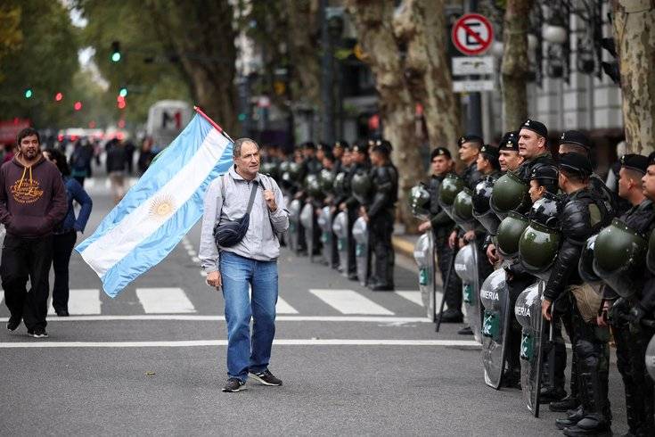 Manifestante segura uma bandeira argentina ao lado dos membros da polícia durante marcha do Primeiro de Maio, em Buenos Aires, na Argentina (Foto: Agustin Marcarian/Reuters)