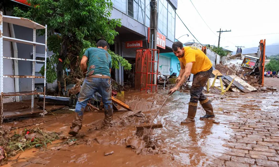 Moradores limpam rua tomada por lama no RS (Gustavo Mansur/Palácio Piratini)
