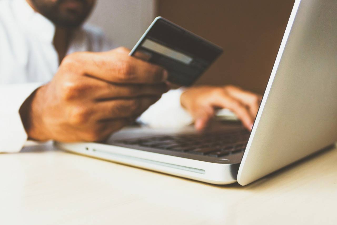 homem com cartão de crédito na mão digitando no notebook