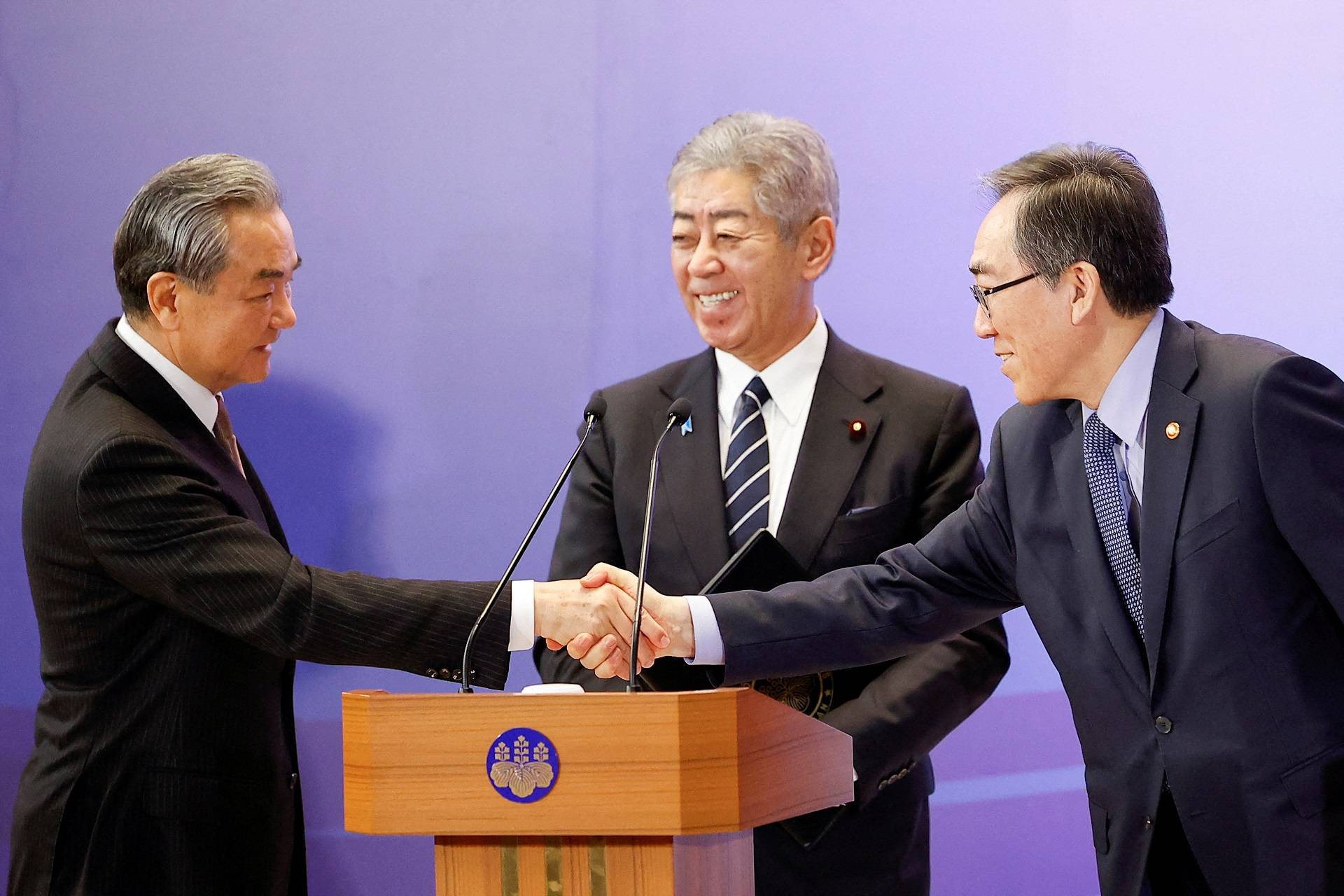 O ministro das Relações Exteriores chinês Wang Yi e o ministro das Relações Exteriores sul-coreano Cho Tae-yul apertam as mãos enquanto o ministro das Relações Exteriores japonês Takeshi Iwaya sorri durante uma coletiva de imprensa conjunta após suas discussões na 11ª Reunião Trilateral de Ministros das Relações Exteriores (Japão-China-ROK) em Tóquio, Japão, em 22 de março de 2025. Rodrigo Reyes Marin/Pool via REUTERS