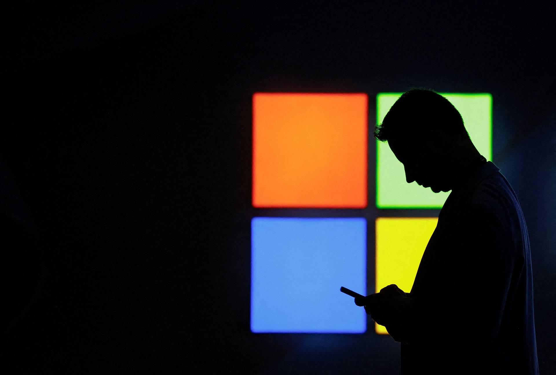 Um homem olha para o celular ao passar pelo estande da Microsoft na feira Mobile World Congress, em Barcelona, ​​Espanha, em 3 de março de 2025. REUTERS/Bruna Casas/Foto de arquivo