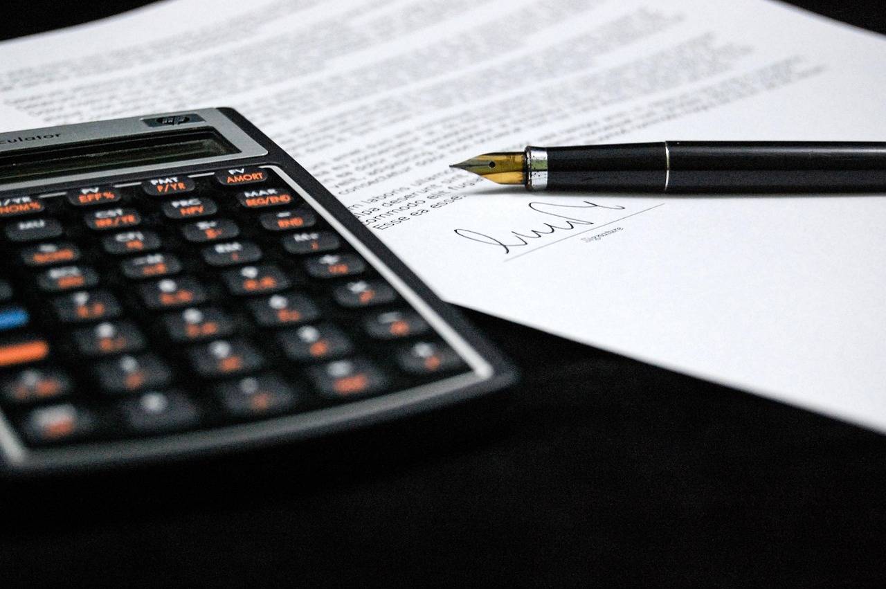 Calculadora e documento com caneta sobre a mesa em alusão a processo de inventário