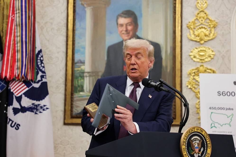 O presidente dos EUA, Donald Trump, segura um modelo do bombardeiro B-2, enquanto ele e o CEO da Apple, Tim Cook, apresentam o anúncio do investimento de US$ 100 bilhões da Apple na manufatura dos EUA, no Salão Oval da Casa Branca, em Washington, D.C., EUA, 6 de agosto de 2025. REUTERS/Jonathan Ernst

