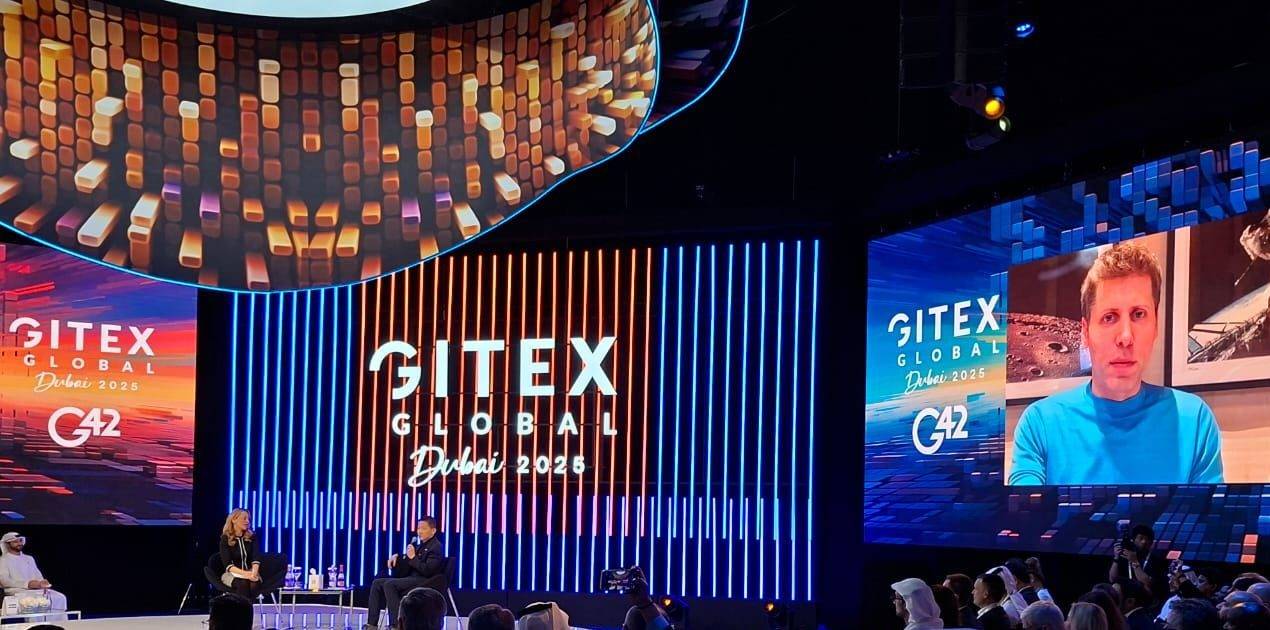 Sam Altman (no telão) e Peng Xiao participam de debate durante o GITEX Global 2025, em Dubai (Foto: Roberto de Lira/InfoMoney)