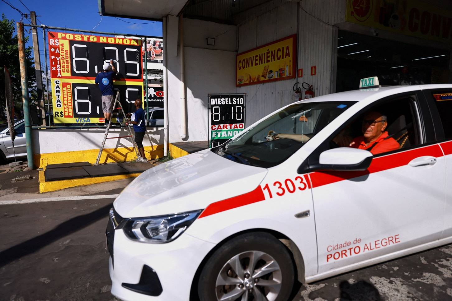 Funcionários de um posto de gasolina ajustam aviso de preços em Porto Alegre (RS) 20 de março de 2026. REUTERS/Diego Vara