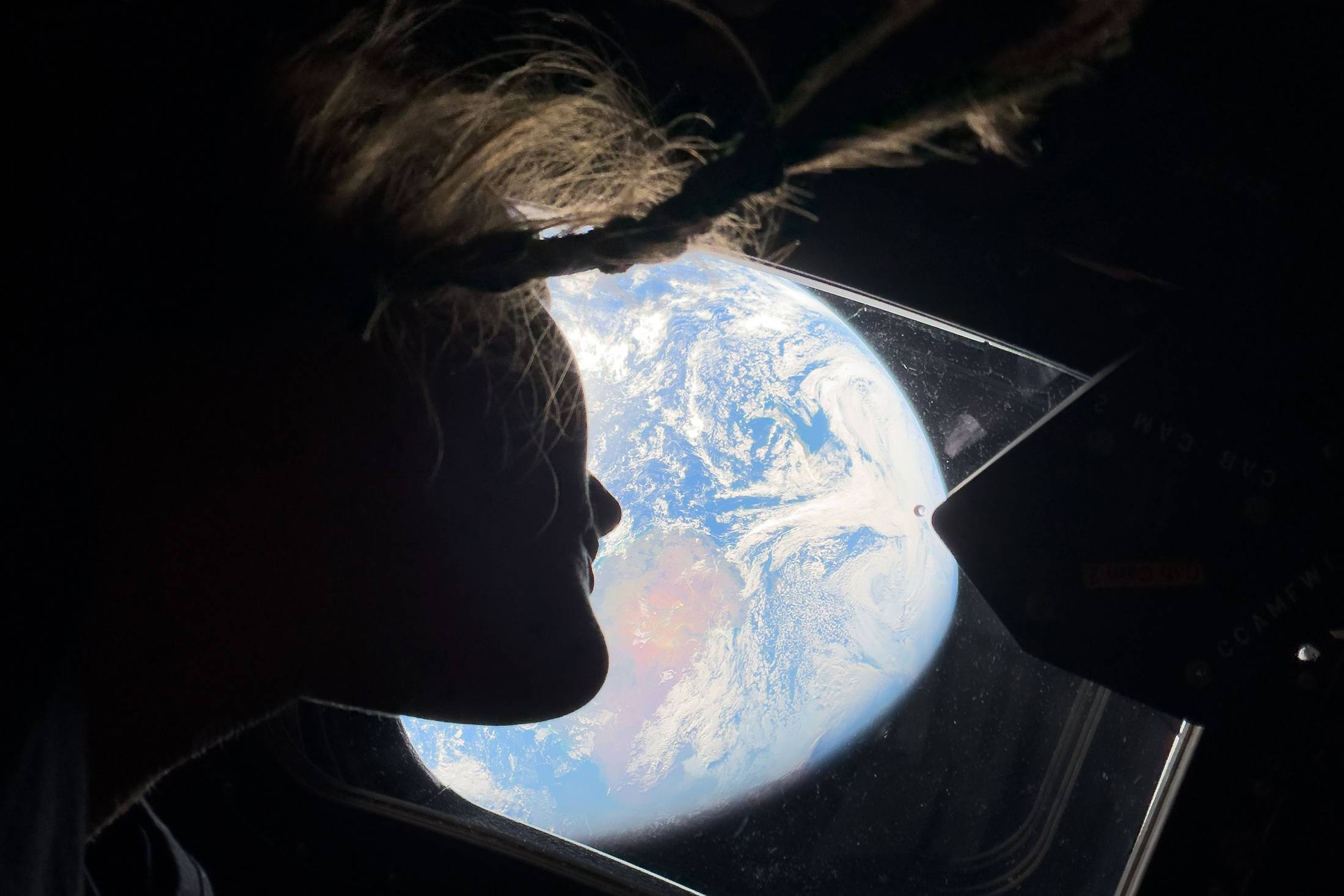 A astronauta Christina Koch olha pela janela principal da cabine da espaçonave Orion, em direção à Terra, enquanto a tripulação viaja rumo à Lua em 4 de abril (Divulgação/Nasa)