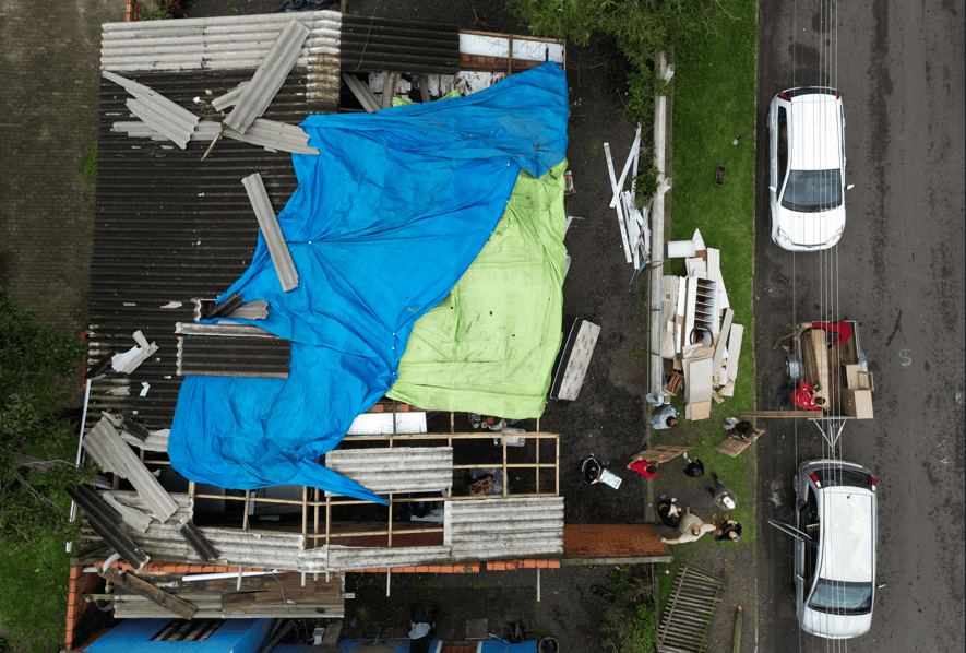 Uma imagem aérea mostra moradores recuperando pertences do lado de fora de uma casa, após ventos fortes arrancarem parte do telhado durante uma chuva intensa em Osório, Brasil, em 28 de julho de 2026.