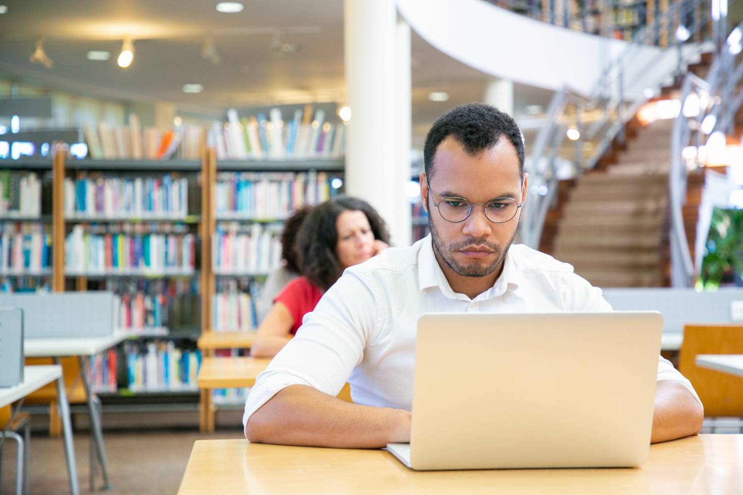 Estudante adulto masculino concentrado fazendo pesquisas na biblioteca